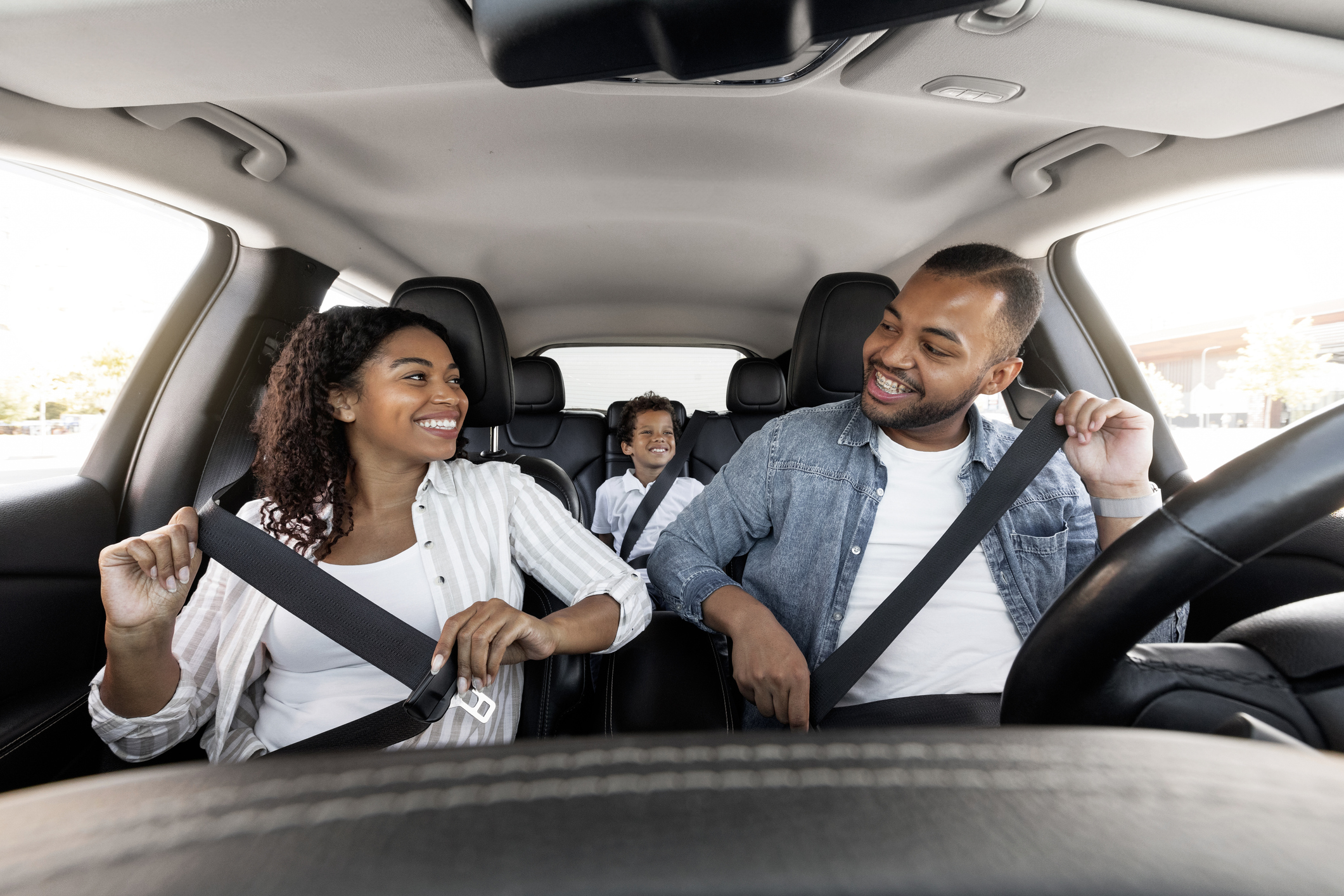 Familie im Auto. Alle tragen Sicherheitsgurte. Kind im Rücksitz.